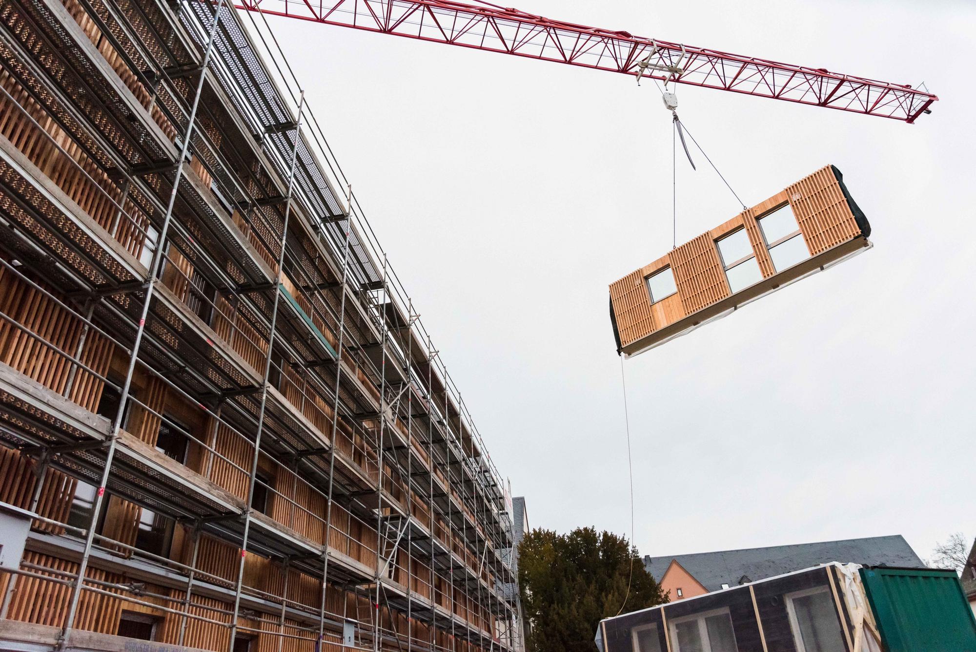 Crane installation of a prefabricated timber façade element at Collegium Academicum Heidelberg